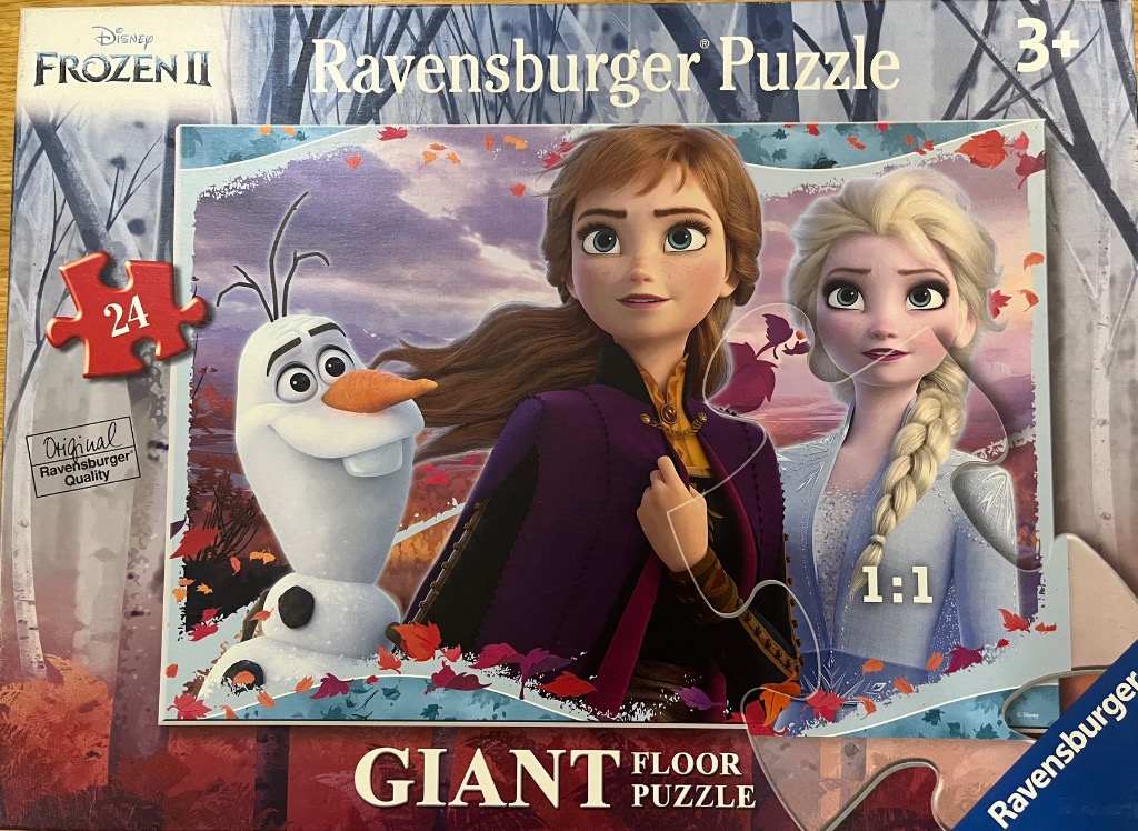 Anna, Elsa, and Olaf from Frozen 2 standing in a forest scene with autumn leaves.