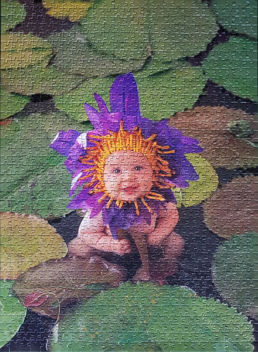 A baby wearing a purple and orange flower costume, sitting on a lily pad.
