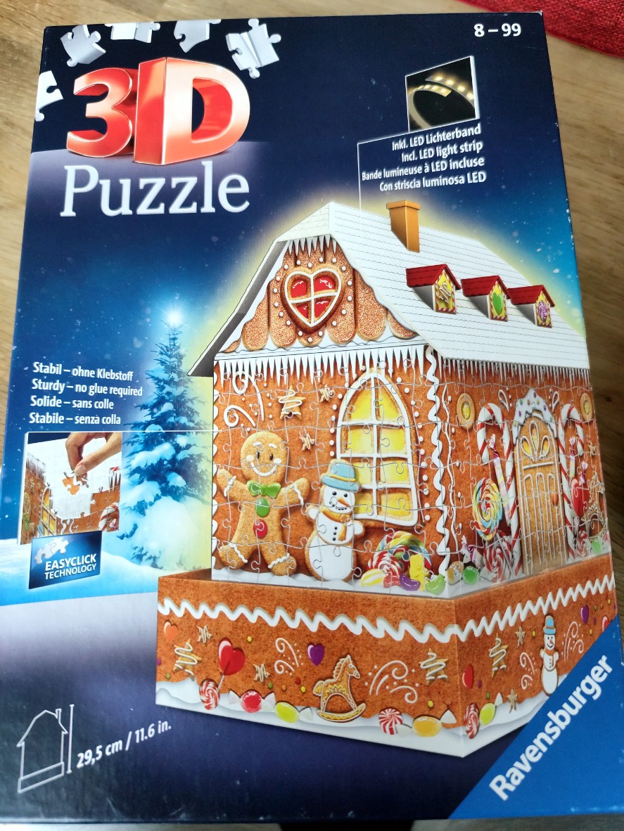 A gingerbread house with Christmas candy decorations against a snowy, dark blue winter sky.