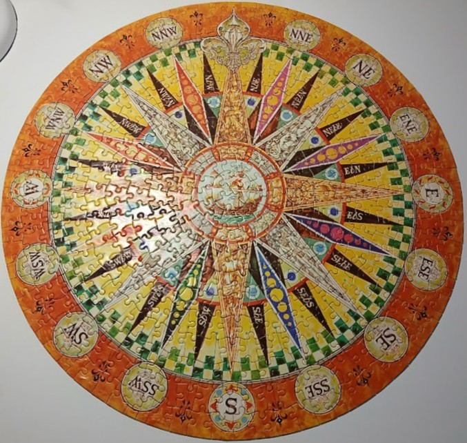A circular vintage-style nautical compass rose illustration with cardinal directions and a central sailing ship.