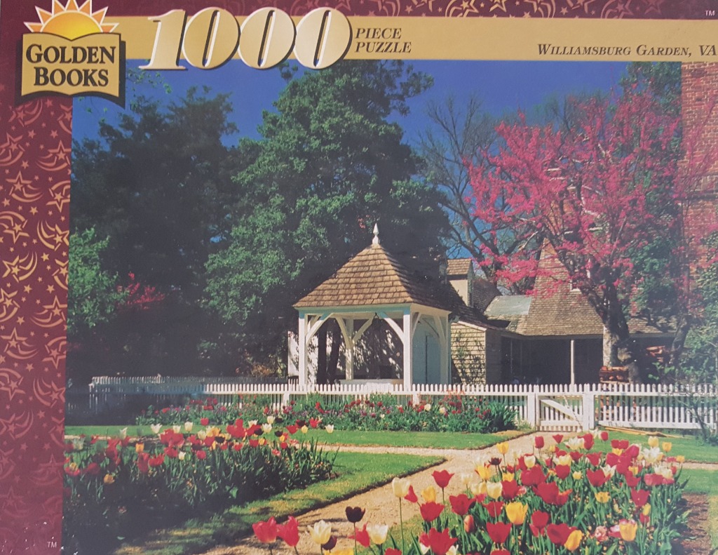 A sunny garden in Williamsburg featuring a white gazebo, a picket fence, and beds of vibrant red and yellow tulips.
