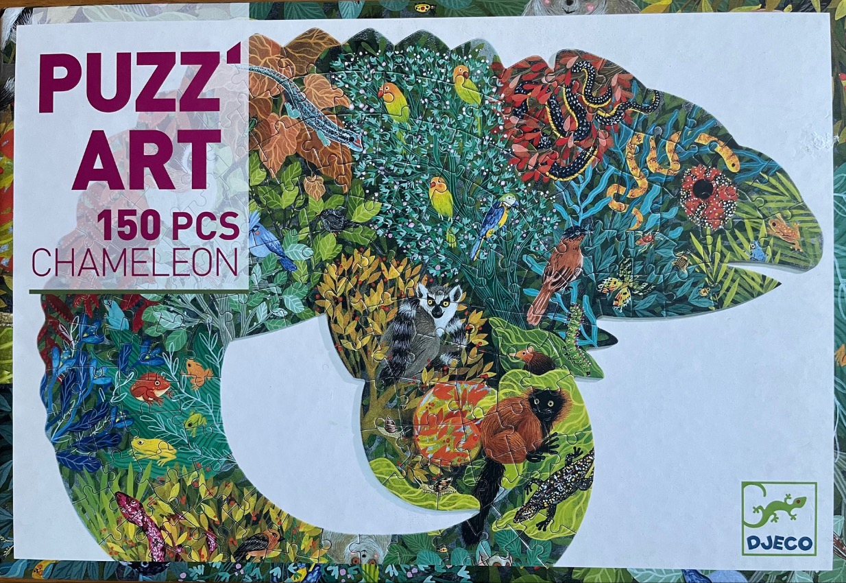 A die-cut chameleon shaped illustration filled with a dense jungle scene of animals and plants.