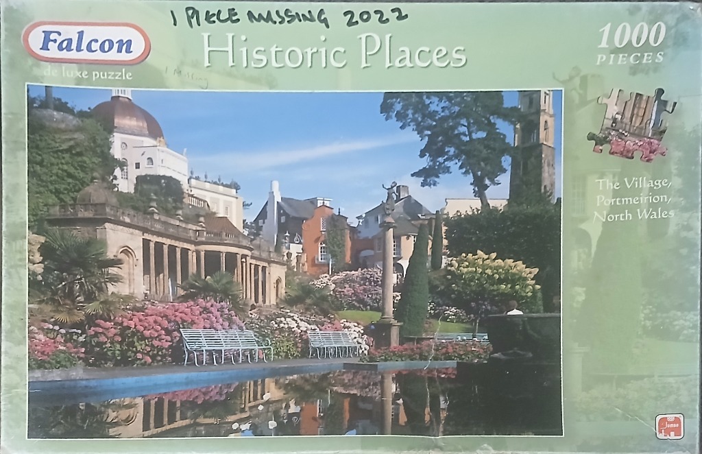 A sunny, colorful scene of Portmeirion village in North Wales with a reflecting pool and blooming flowers.