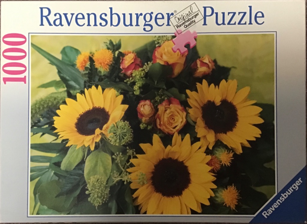 A lush floral arrangement featuring large yellow sunflowers and orange roses against a soft yellow background.