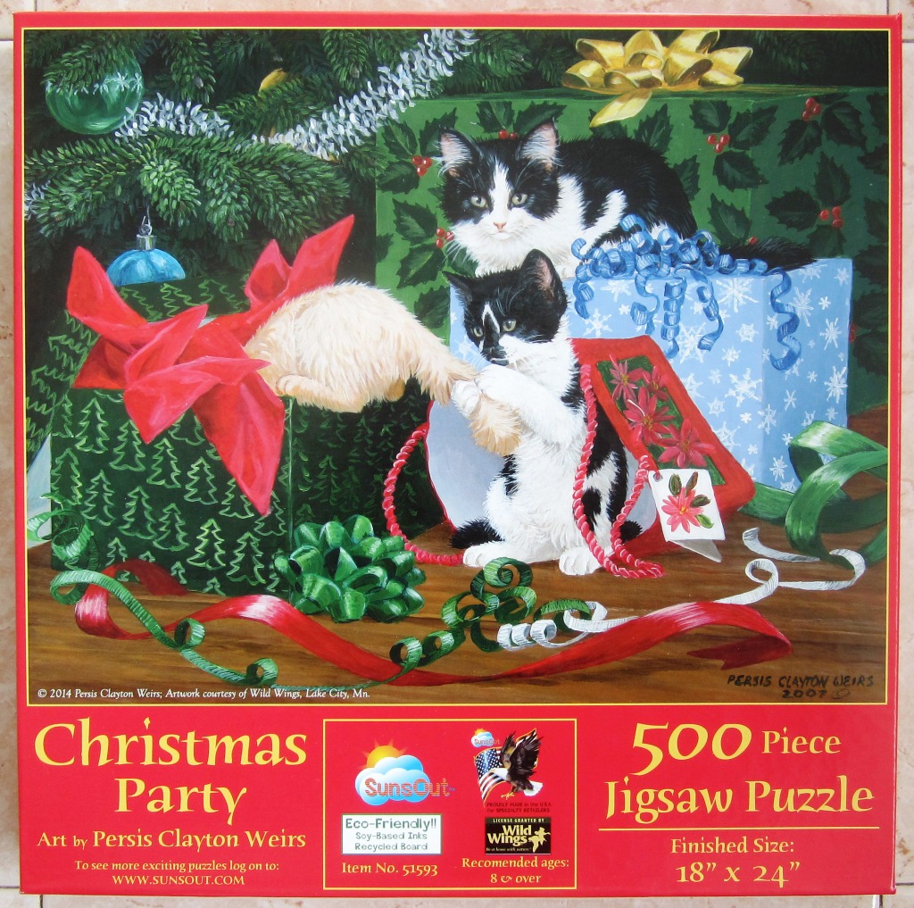 Two black and white kittens playing with gift-wrapped boxes under a Christmas tree