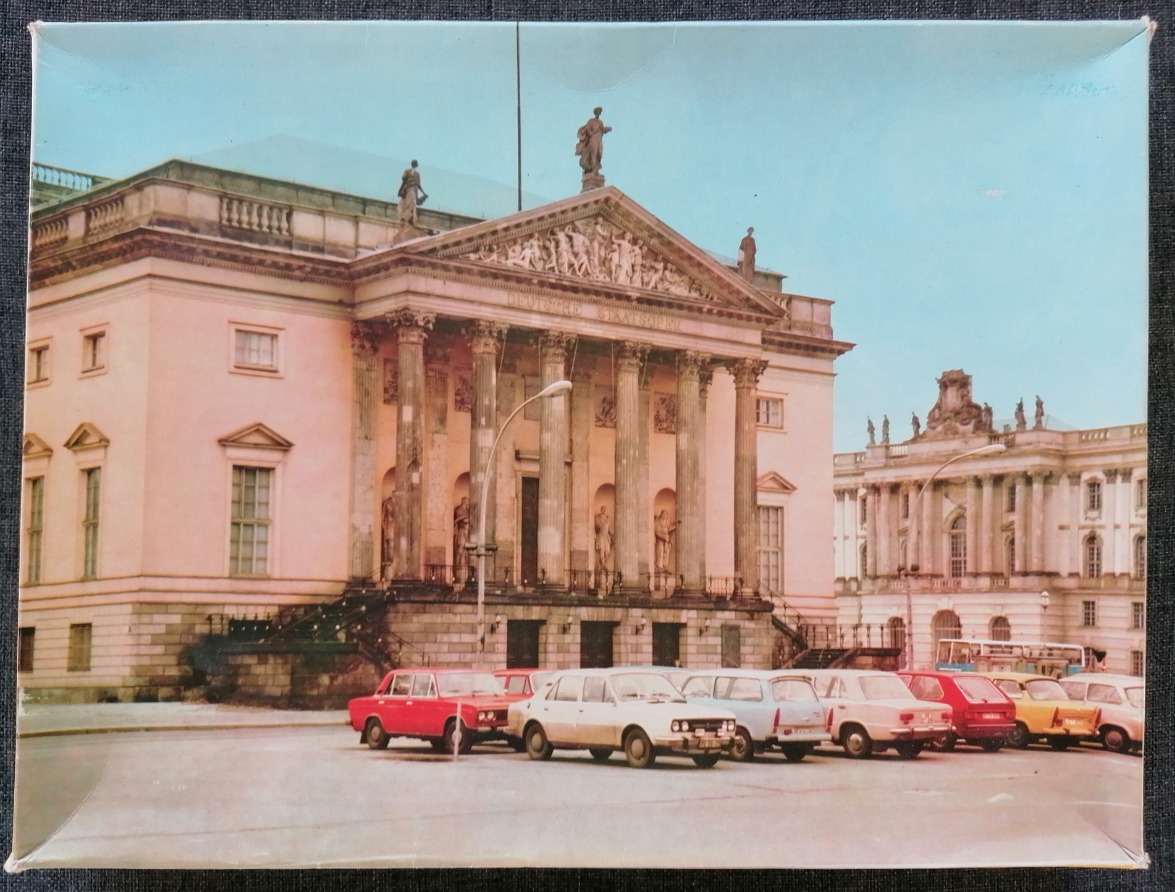 View of the Berlin State Opera with cars parked in front in a vintage photograph