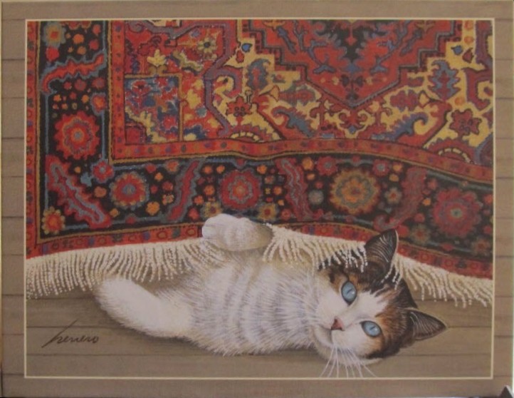 A calico cat lying on a wooden floor partially hidden beneath the fringed edge of a red and black oriental rug.