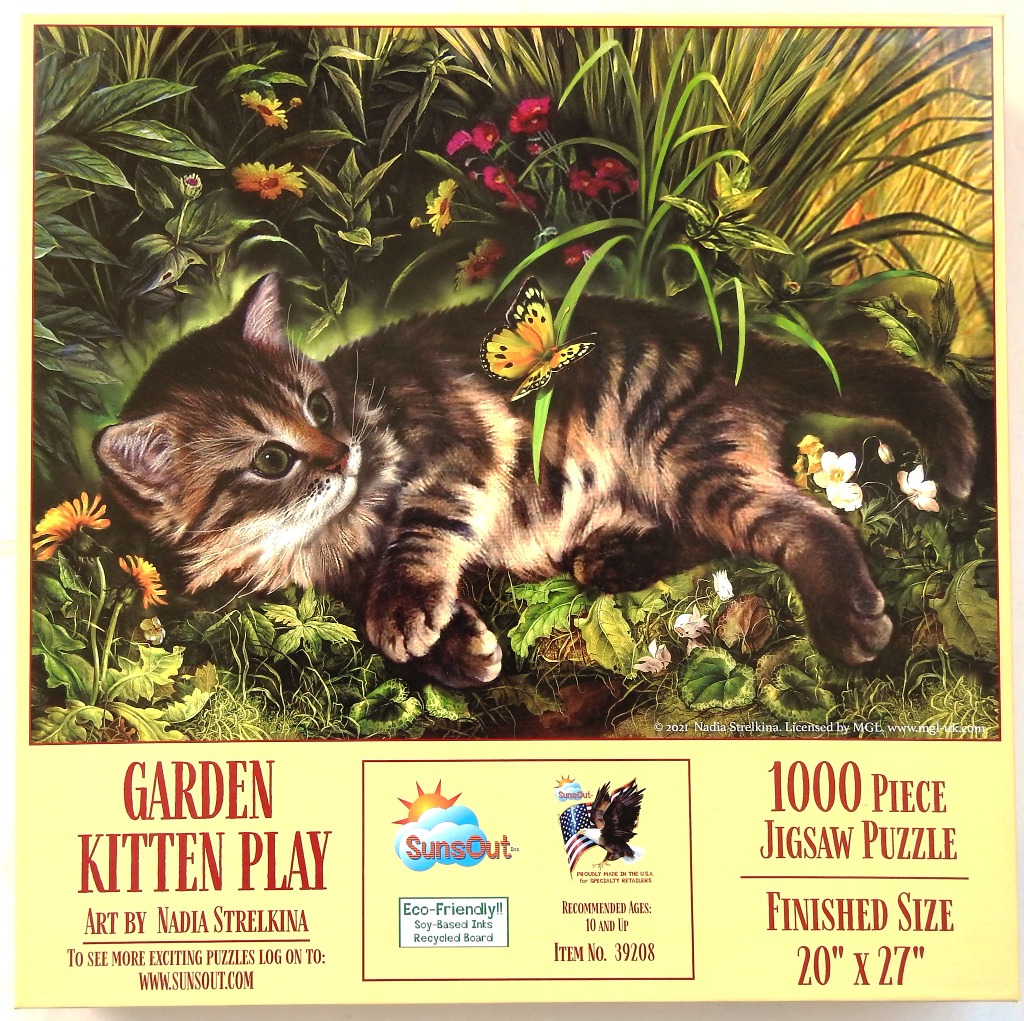 A fluffy tabby kitten lying in a lush garden with a butterfly landing on its back.