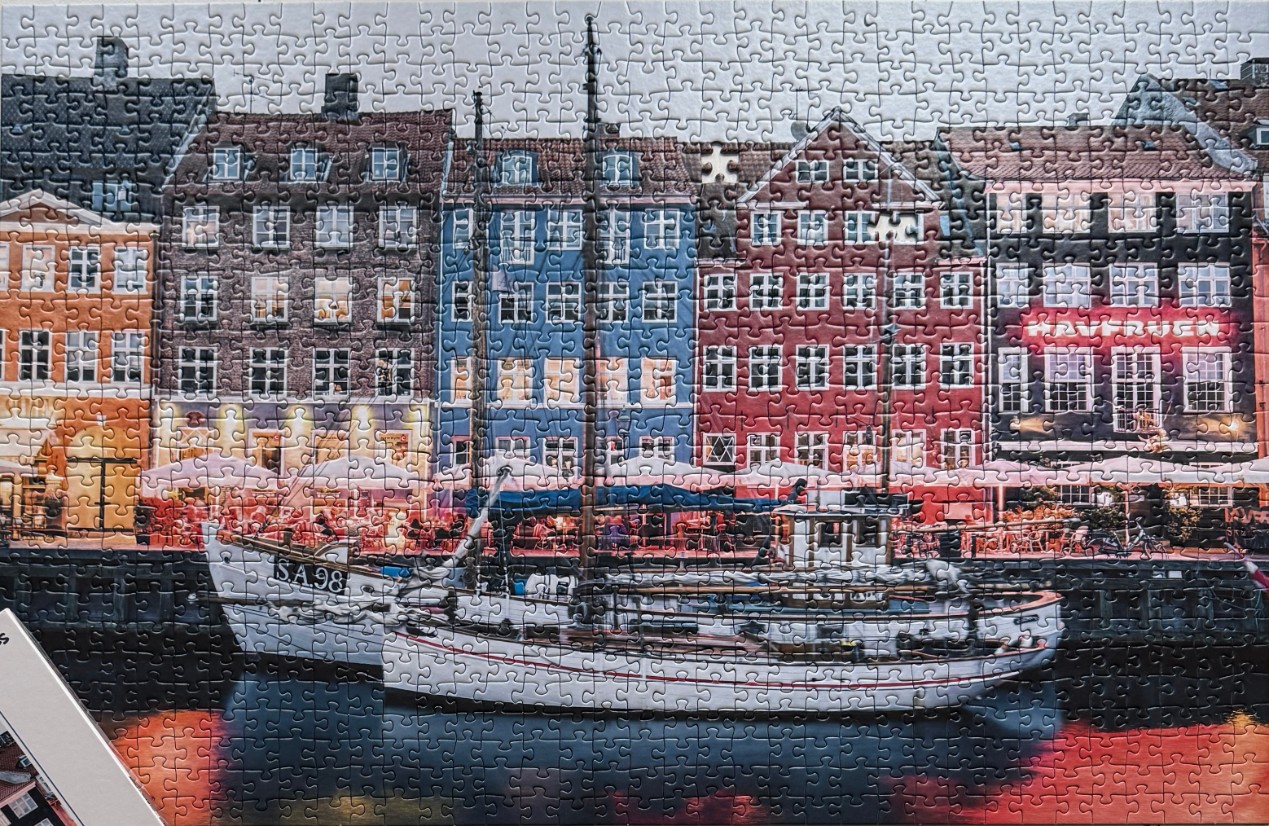 A white fishing boat moored on a canal in front of colorful gabled buildings in Copenhagen, Denmark.
