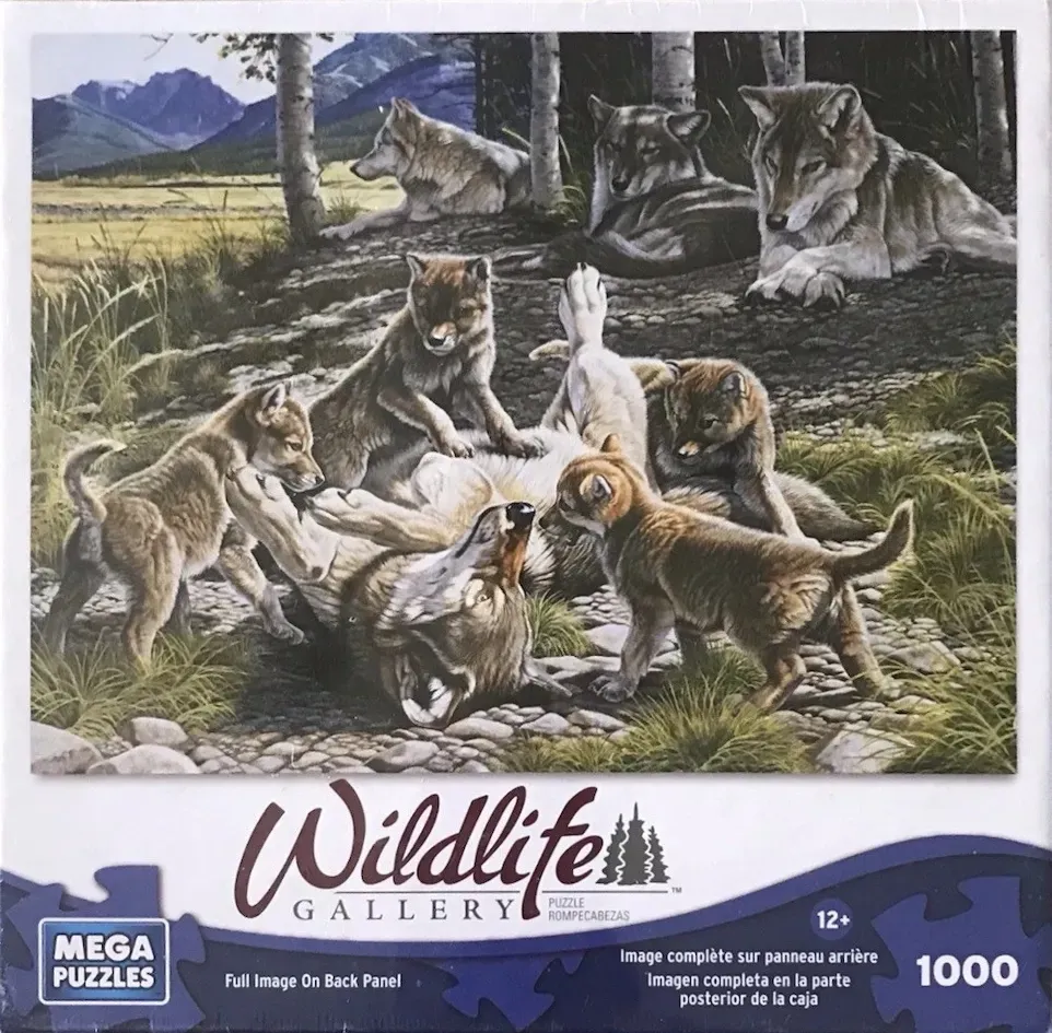 A mother wolf playing with her pups in a forest clearing with mountains in the background