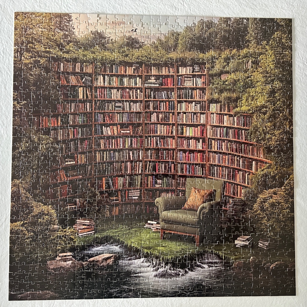 A cozy armchair sits in a library carved into a lush, green forest with a stream flowing in the foreground.