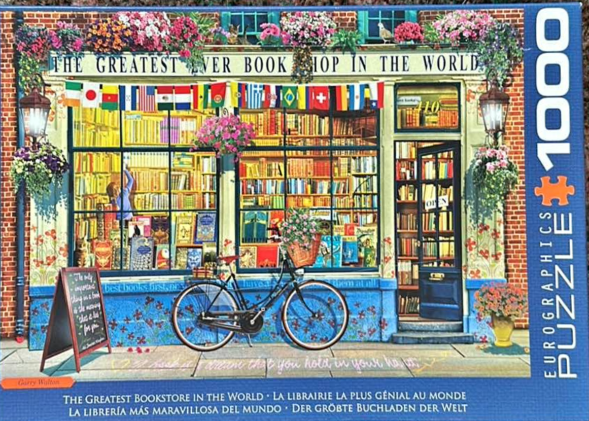 A charming bookstore storefront decorated with flowers, international flags, and a bicycle out front.