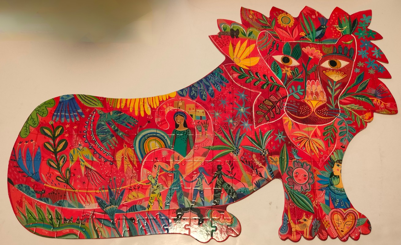 A whimsical illustration of a lion silhouette filled with intricate patterns, people, plants, and animals in red and pink.