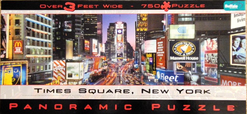A panoramic nighttime photograph of Times Square in New York City with bright neon signs and busy traffic.