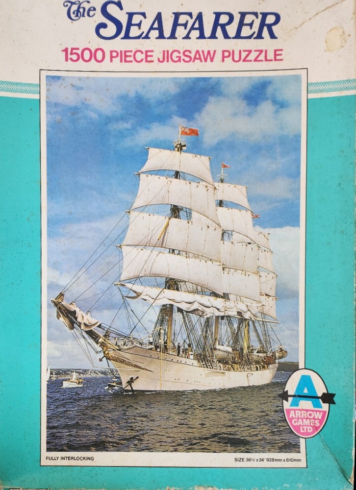 A tall ship with white sails sailing on the ocean under a blue sky.