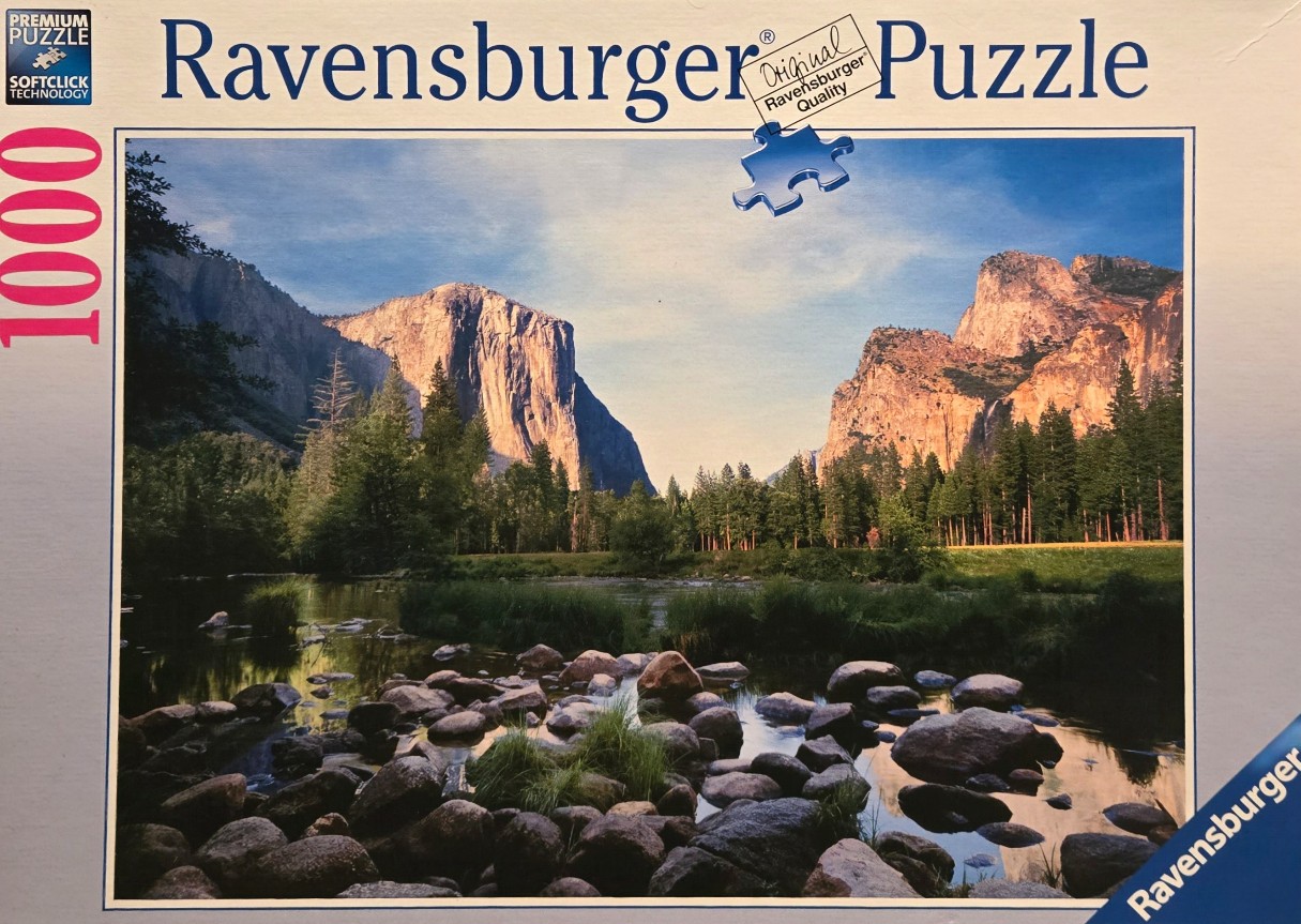 A scenic landscape photograph of Yosemite Valley with El Capitan rising above a river filled with smooth river stones.