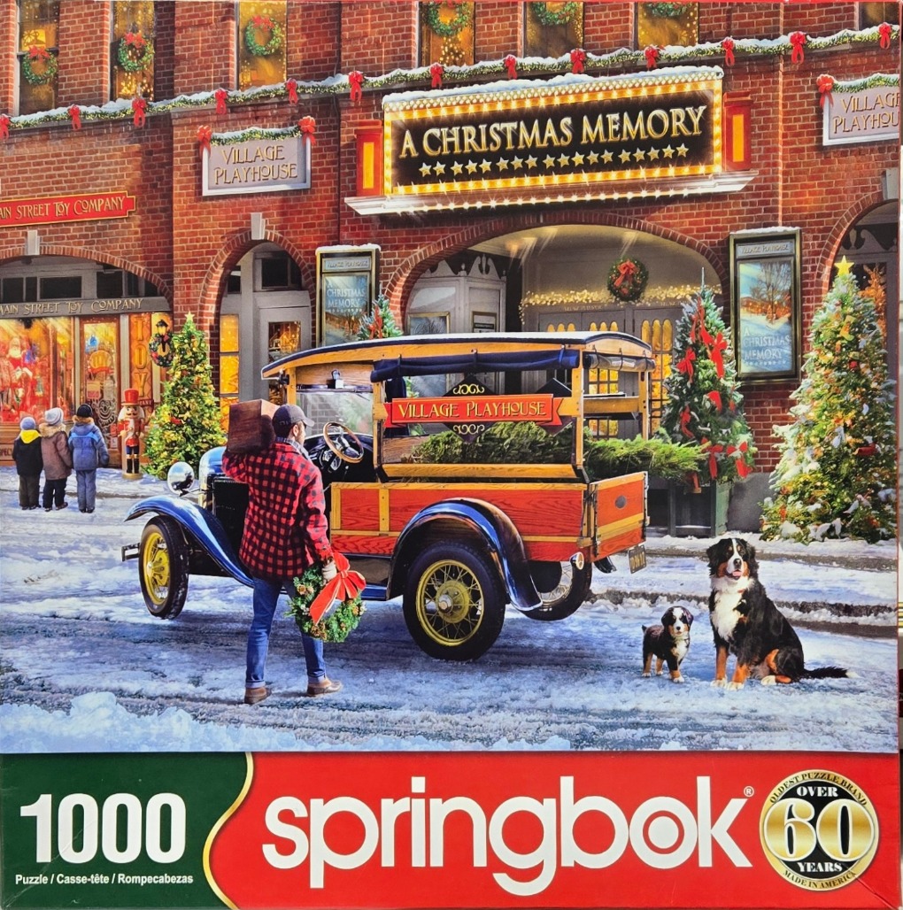 A man with a wreath and a wooden truck in front of a theater decorated for Christmas.