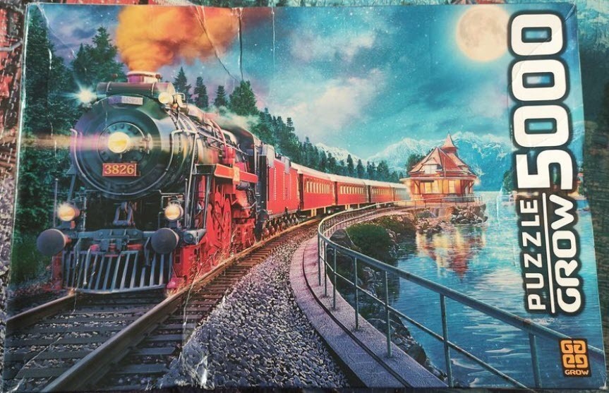 A vintage steam locomotive pulling passenger cars along a moonlit lakeside railway.