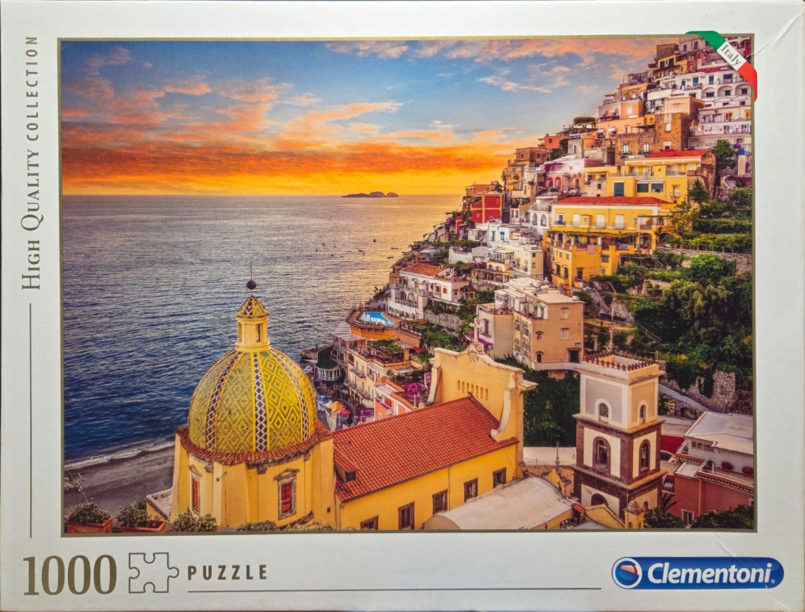 A stunning sunset view over the Positano coastline in Italy, featuring a prominent yellow-tiled church dome.