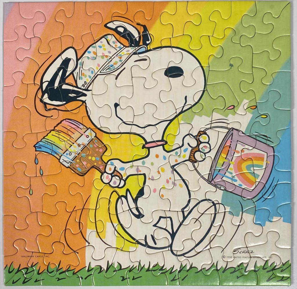 Snoopy the dog painting a rainbow, with a colorful paint bucket and brush in his hands.