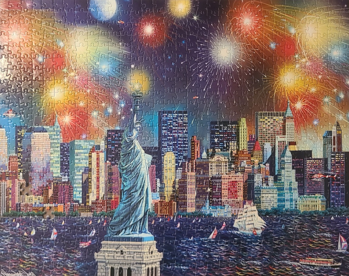 The Statue of Liberty standing before a New York City skyline illuminated by celebratory fireworks.