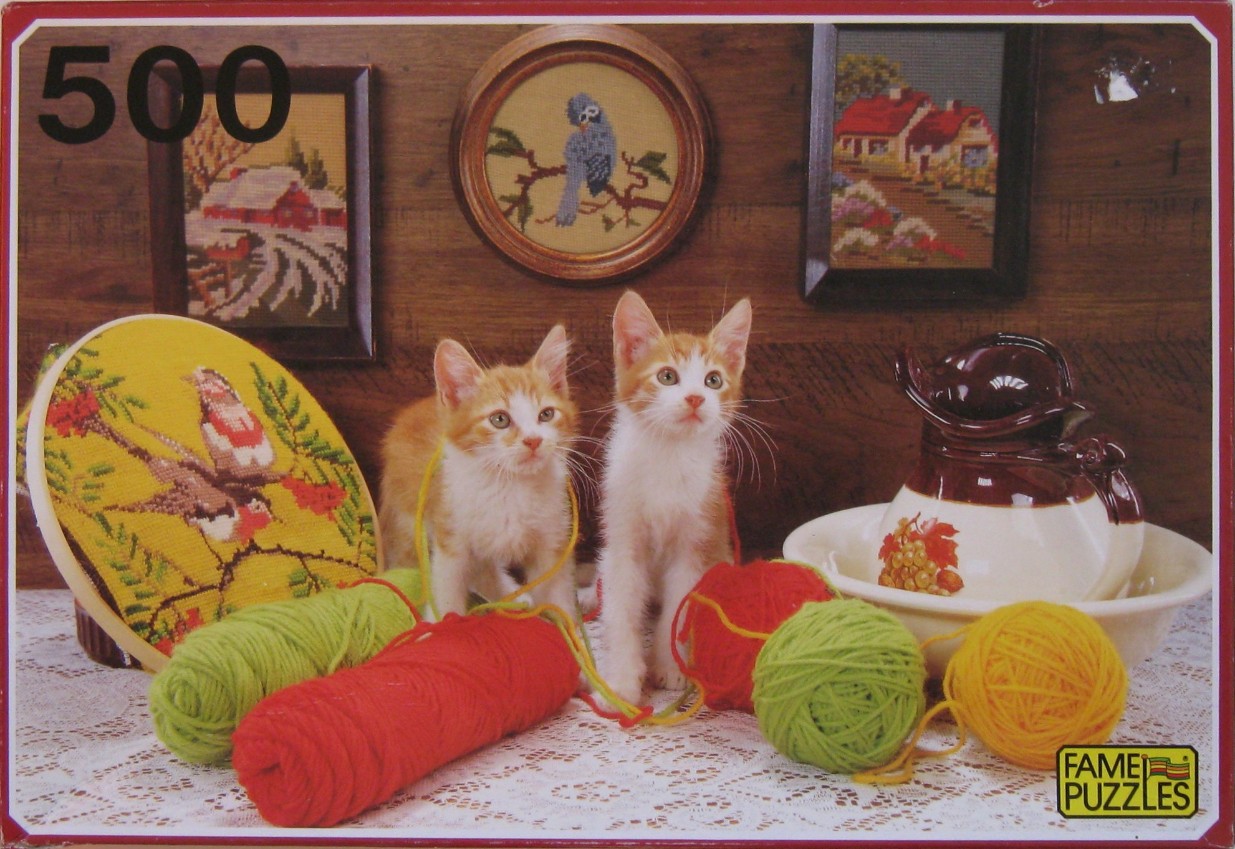 Two ginger and white kittens sitting among balls of yarn and embroidery crafts in a rustic room.
