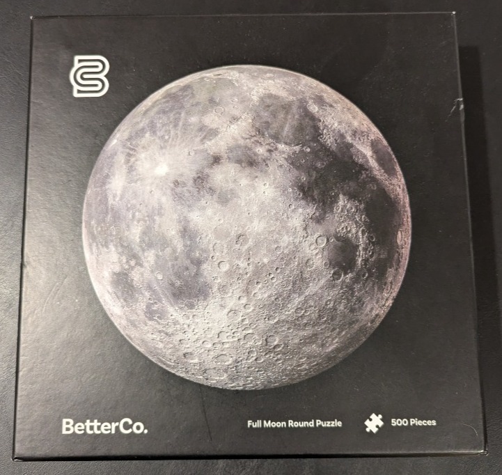 A detailed photographic depiction of a full moon centered against a plain black background.