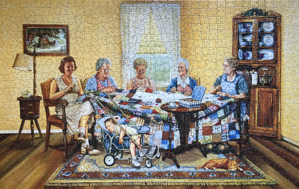 Illustration of five elderly women gathered around a large colorful quilt in a cozy, sunlit living room.