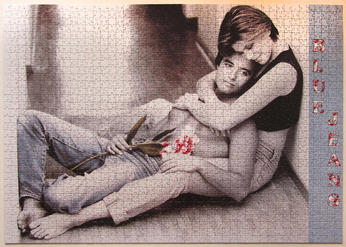 A black and white photograph of a young couple embracing on the floor with the text BLUE JEANS printed on the side.
