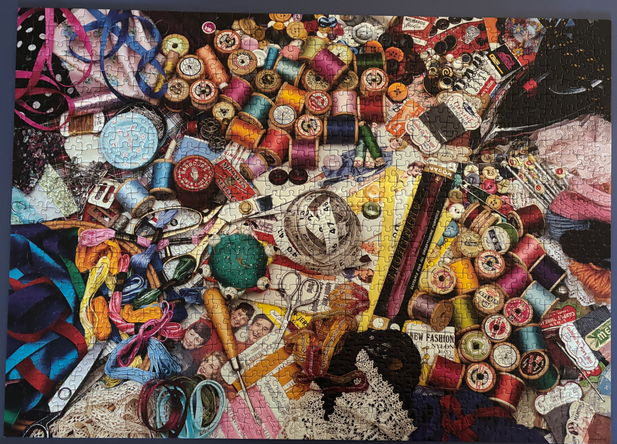 A cluttered, vintage-themed collection of sewing supplies including thread spools, lace, ribbons, and needles.