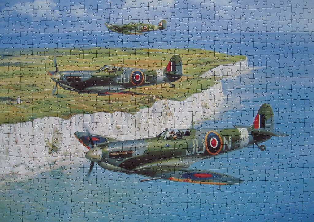 Three World War II fighter planes flying in formation over the White Cliffs of Dover.