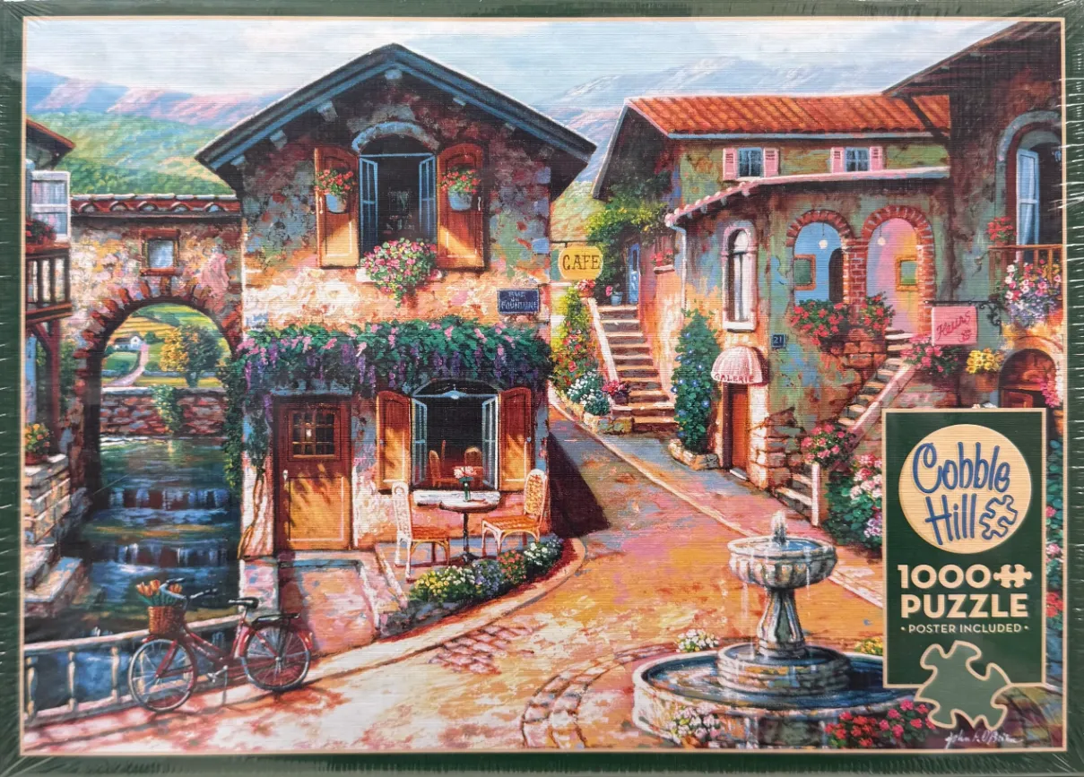 A charming European village scene with stone buildings, a cafe, a fountain, and a red bicycle.