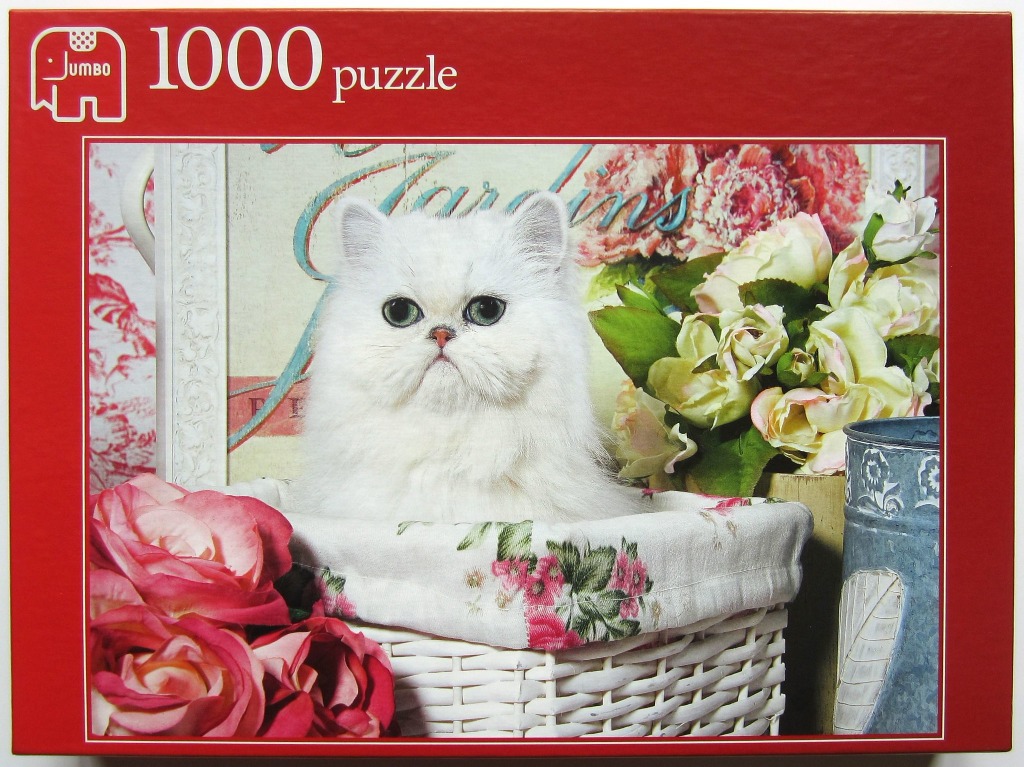 A fluffy white Persian cat sitting in a white wicker basket filled with roses and a decorative sign.