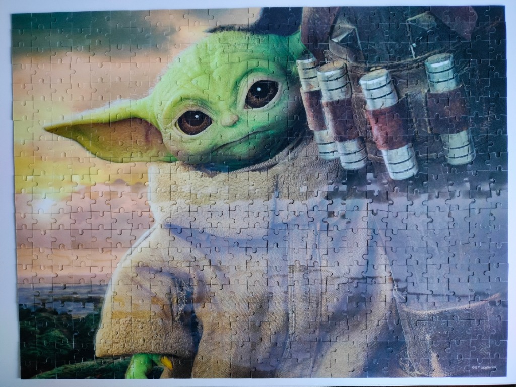 A close-up illustration of the green, large-eared character Grogu wearing a tan robe against a sunset landscape.