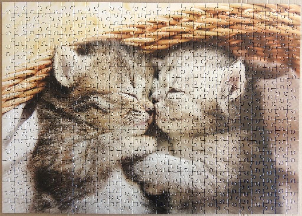 Two tabby kittens napping curled together inside a woven wicker basket.