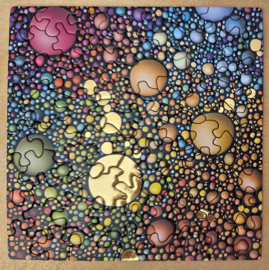 An abstract composition of densely packed, multi-coloured spheres of various sizes against a black background.