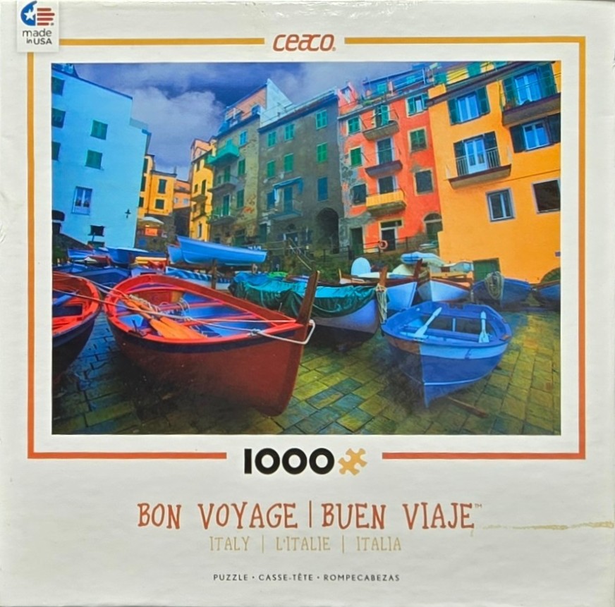 A colourful Italian seaside village with several small fishing boats docked on a paved harbor in the foreground.