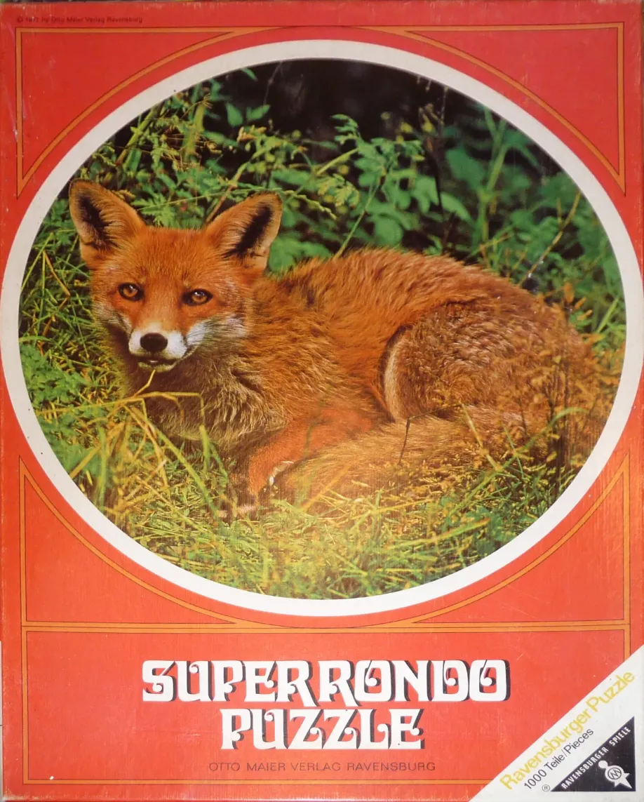 A photograph of a red fox resting in tall, lush green grass inside a circular frame.