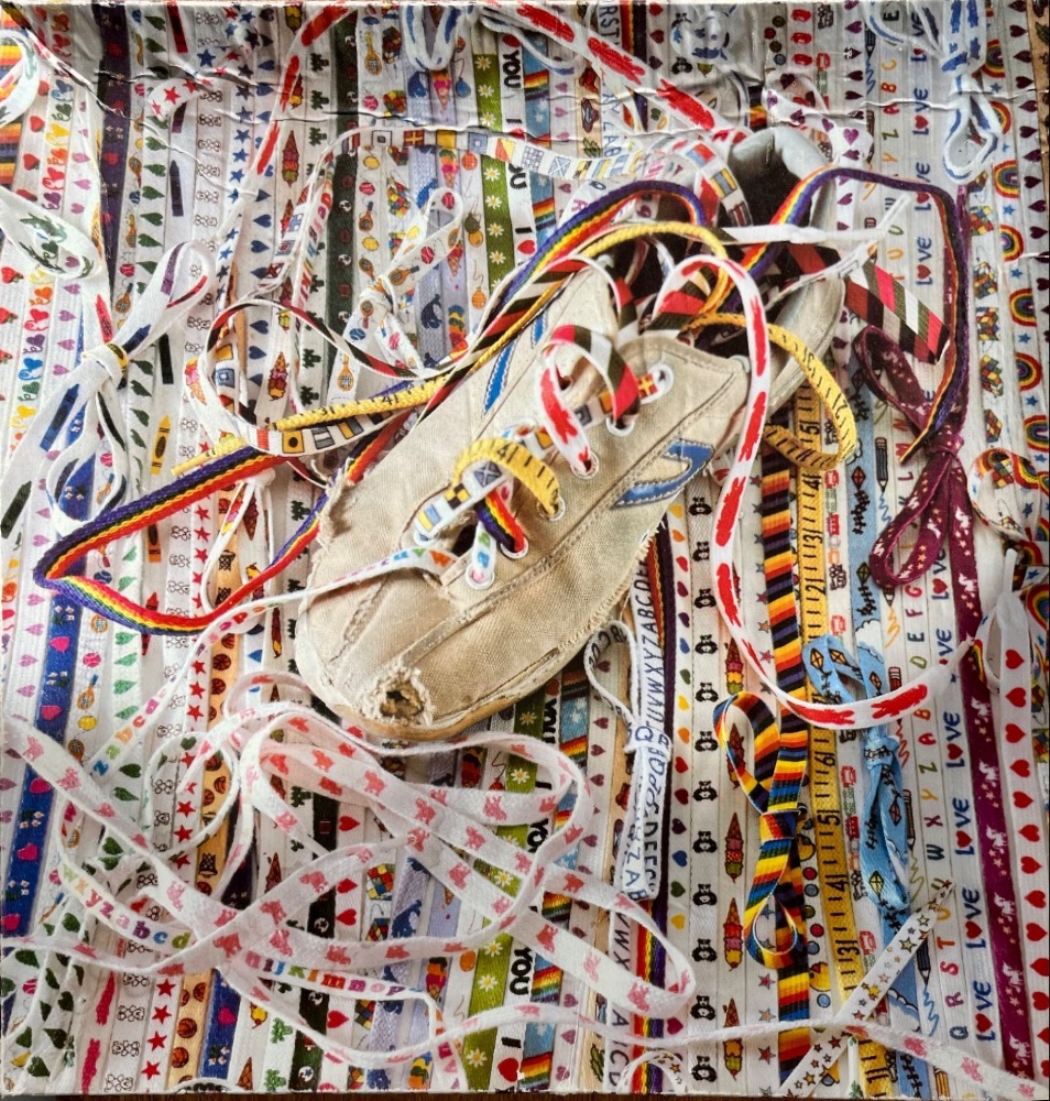 A worn, cream-colored sneaker surrounded by a chaotic tangle of colorful patterned ribbons and shoelaces.