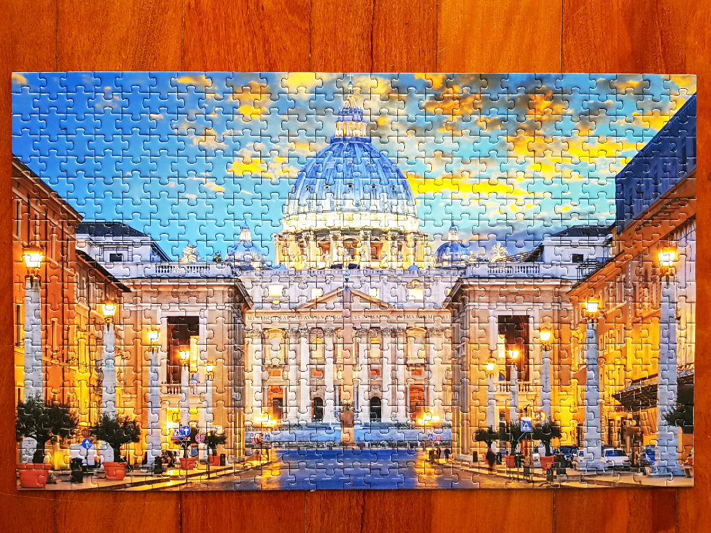 St. Peter's Basilica dome under a sunset sky viewed from a city street