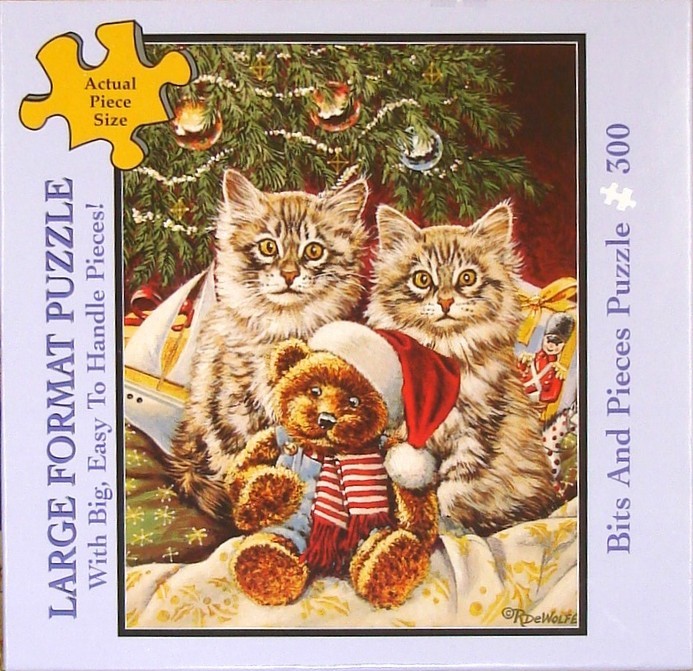 Two fluffy tabby kittens sitting behind a teddy bear in front of a Christmas tree