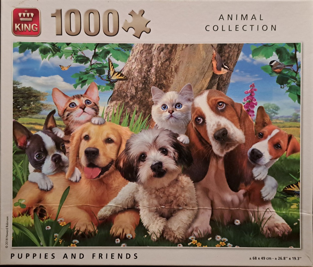 A group of diverse puppies and kittens sitting together in a grassy meadow under a tree.