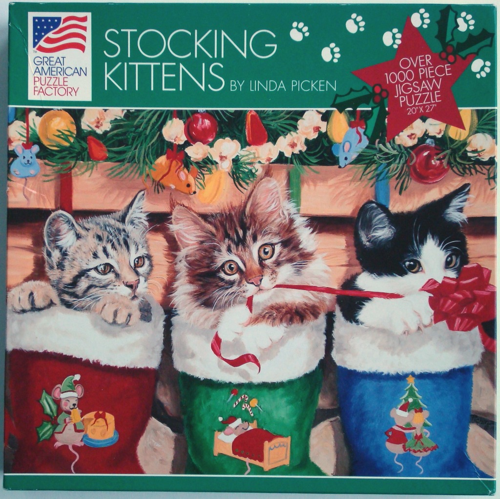 Three kittens sitting in individual Christmas stockings hanging on a wooden wall.
