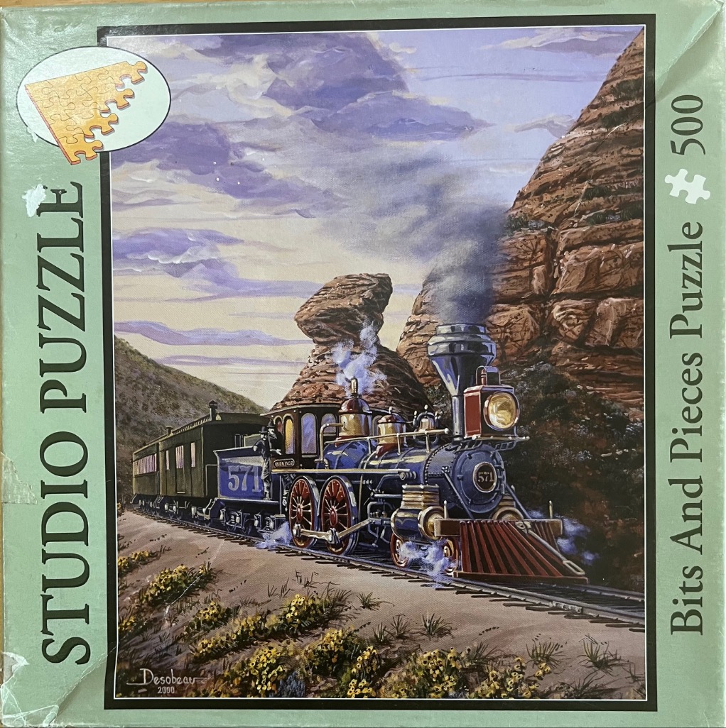 A vintage steam locomotive pulling passenger cars through a rocky desert canyon.