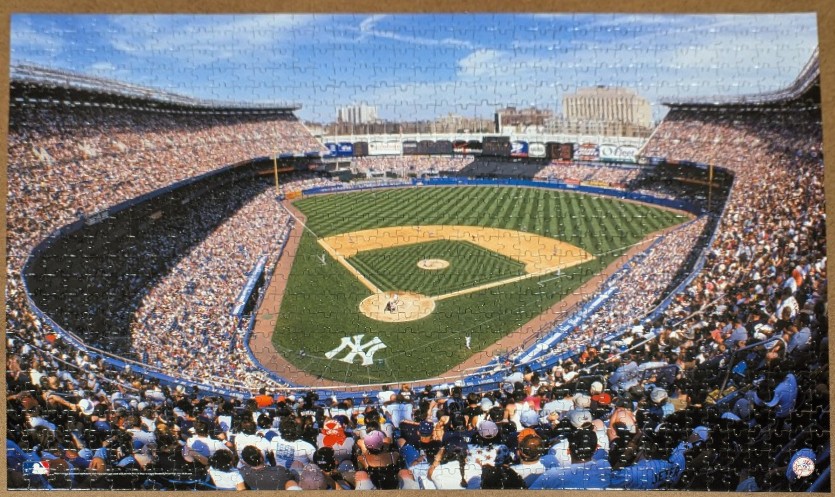 Wide-angle photograph of Yankee Stadium filled with fans during a baseball game on a clear day.