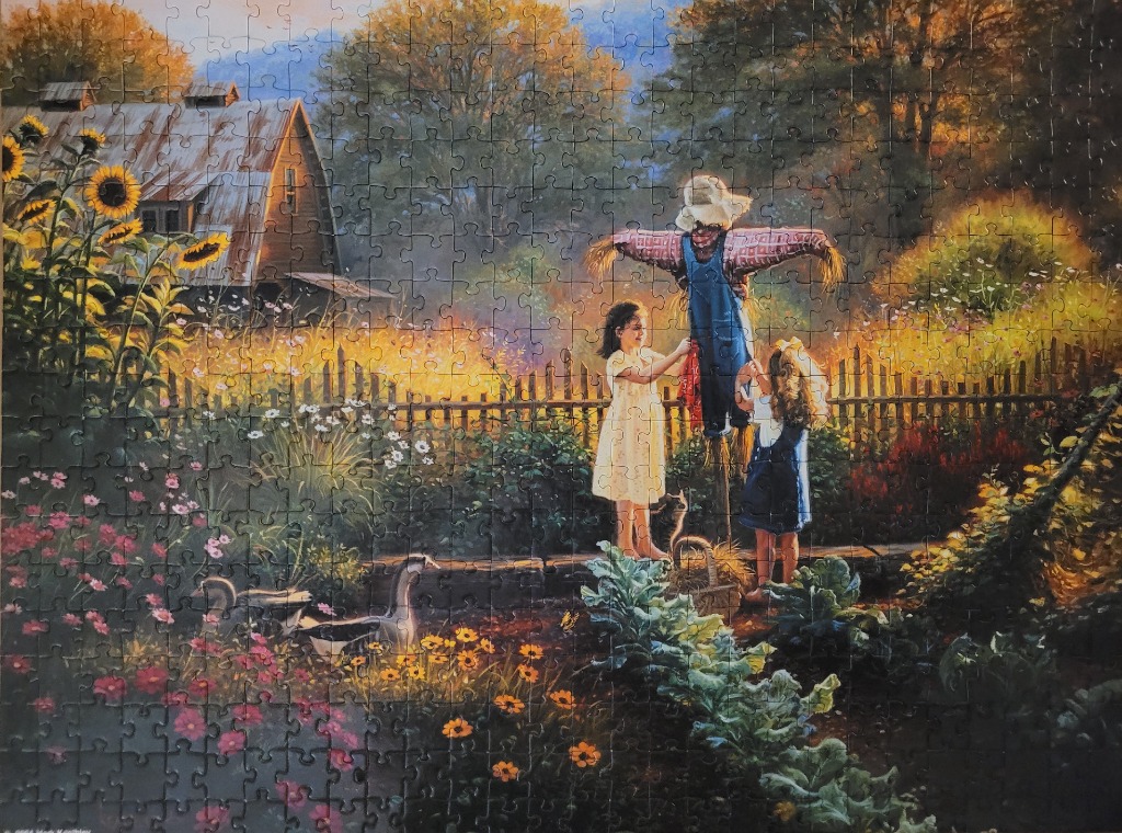 Two young girls standing in a sunlit garden next to a scarecrow, near a wooden barn and a patch of sunflowers.