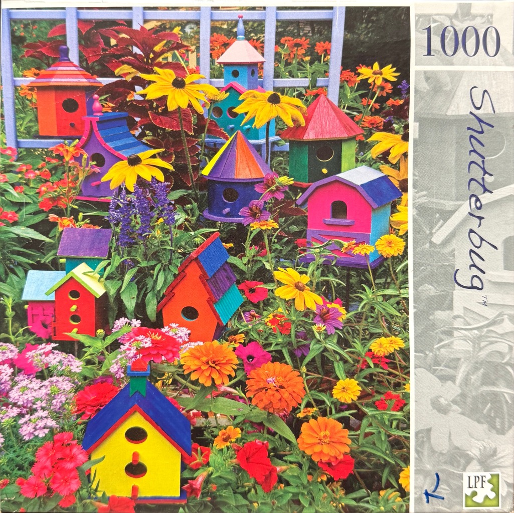 A collection of colorful decorative birdhouses nestled among vibrant flowers in a lush garden.