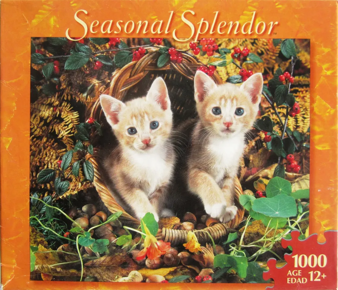 Two ginger tabby kittens peeking out of a woven basket surrounded by autumn foliage and berries.
