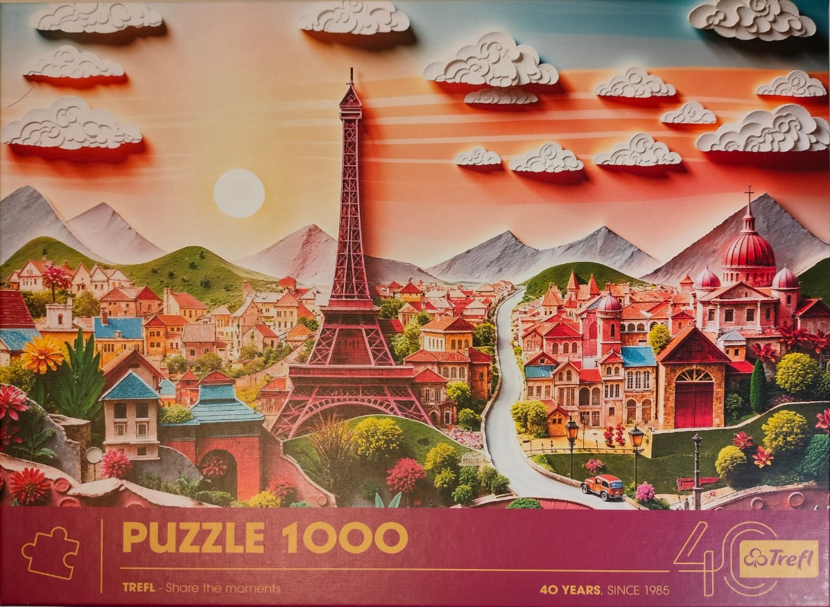 A whimsical 3D-style papercraft illustration of the Eiffel Tower in a colorful European village at sunset.