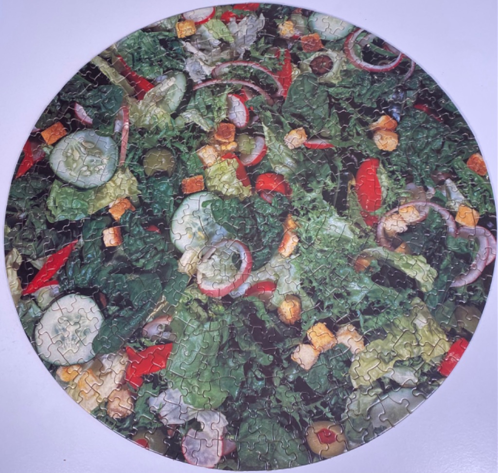 Circular close-up photograph of a fresh, colorful green garden salad.